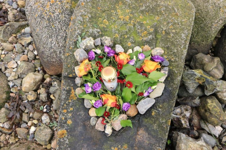 A heart-shaped arrangement of flowers and a candle, ideal for NY sea burials on Long Island.