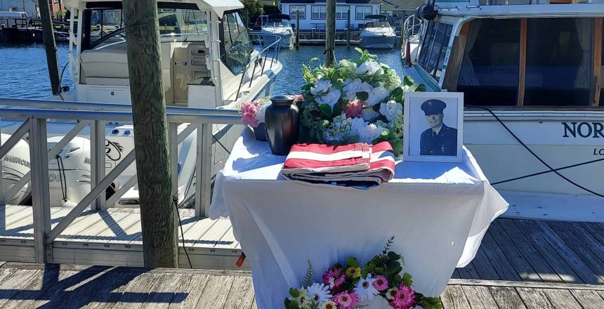 A memorial table with flowers and urn sits by docked boats, honoring loved ones at Sea Burials NY.