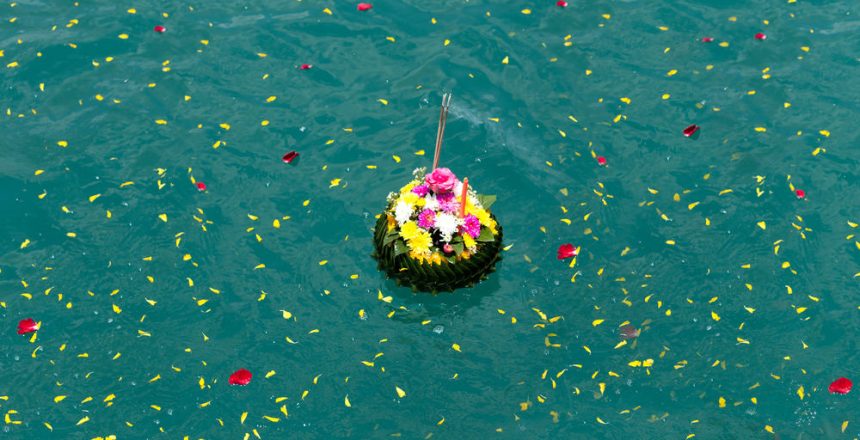 A krathong with flowers and incense floats among petals, evoking NY Sea Burials Long Island tradition.