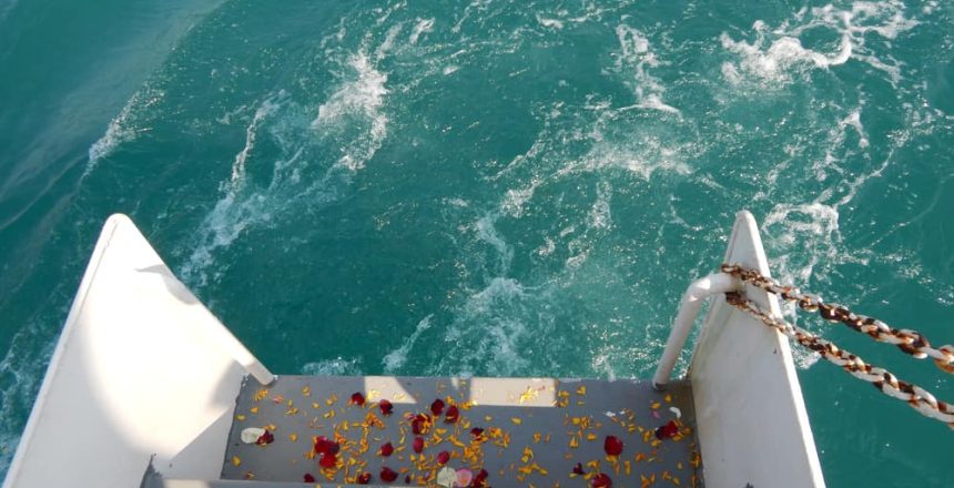 Boat steps with flower petals lead to turquoise water, perfect for Sea Burials Long Island & Queens.